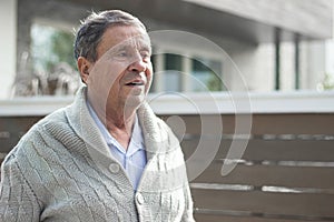 Smiling senior man in front of house