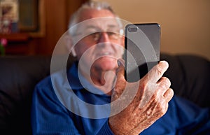 Smiling Senior Man At Home Making Video Call To Family On Mobile Phone
