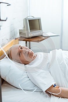 Smiling senior man lying on bed in hospital