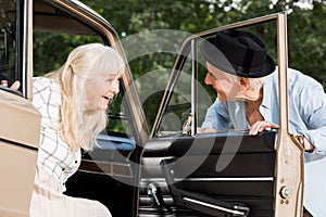 smiling senior man opening car door in front