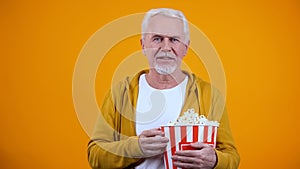 Smiling senior man with pop corn watching exciting film, spending leisure time