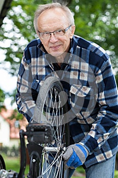 Smiling senior man repairing a bicycle