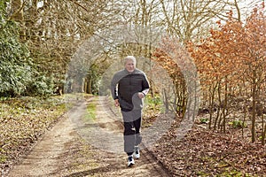 Smiling Senior Man Running In Autumn Countryside Exercising During Covid 19 Lockdown