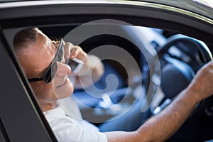 Smiling senior man talking on phone in car