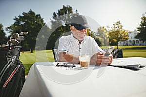 Smiling senior man using his cellphone at his golf clubhouse