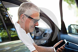 Smiling senior man using smart phone in car