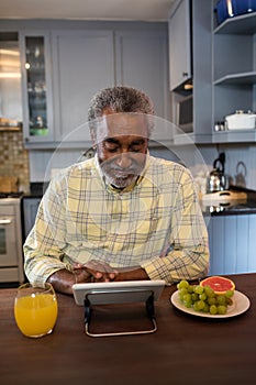 Smiling senior man using tablet computer in kitchen