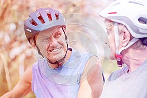 Smiling senior man wearing cycling helmet while looking at woman