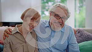 Smiling senior man and woman looking at camera. Husband hugging wife