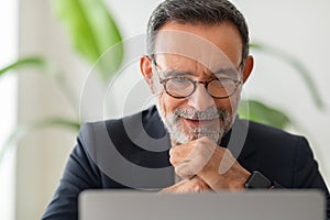 Smiling senior man working attentively on a laptop