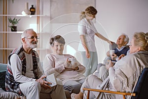 Smiling senior man talking to other residents of the retirement home photo