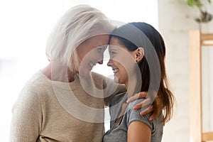 Smiling senior mom hug adult teen daughter