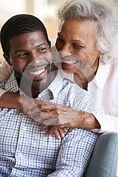 Smiling Senior Mother Hugging Adult Son At Home