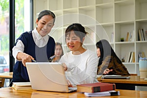 Smiling senior professor helping student woman with laptop during lecture