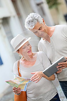 Smiling senior tourists using tablet in the streets