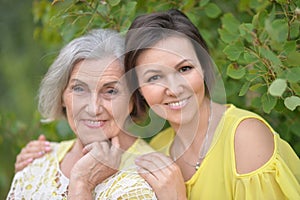 Smiling senior woman with adult daughter in autumnal park