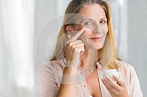 Woman applying anti aging lotion on face