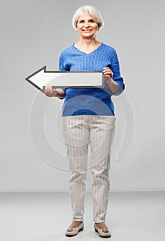 Smiling senior woman with big leftwards arrow