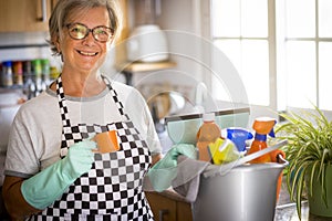 Smiling senior woman busy with house hygiene works stops for a coffee break - precautions against virus infection