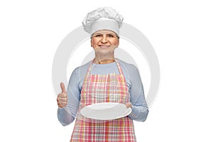 smiling senior woman or chef holding empty plate