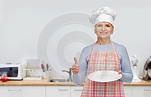 smiling senior woman or chef holding empty plate