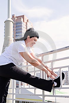 Smiling senior woman doing stretching outdoors on urban background