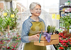 smiling senior woman with garden tools in box