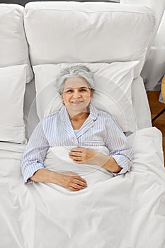 smiling senior woman lying in bed at home bedroom