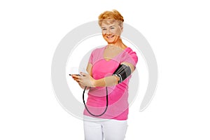 Smiling senior woman measuring blood pressure