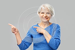 Smiling senior woman pointing fingers to something