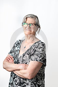 Smiling senior woman posing and looking at camera with arms crossed over isolated white background