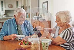 Smiling senior woman pouring her husband a coffee over breakfast