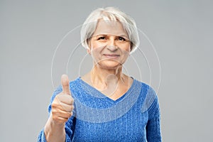 Smiling senior woman r showing thumbs up