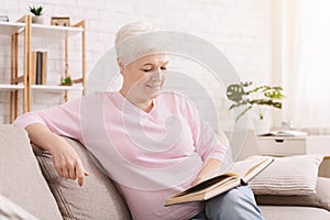 Smiling senior woman reading book at home