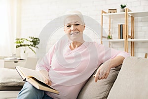 Smiling senior woman reading book at home