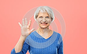 Smiling senior woman showing palm or five fingers