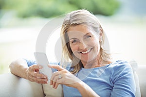 Smiling senior woman using mobile phone in living room