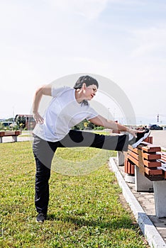 Smiling senior woman warming up stretching outdoors in the park