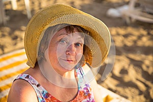 Smiling Senior woman wearing hat at beach on sunbed