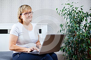 Smiling senior woman working on laptop at home.