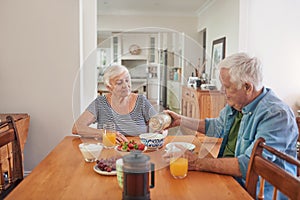 Smiling seniors enjoying a healthy breakfast at home together