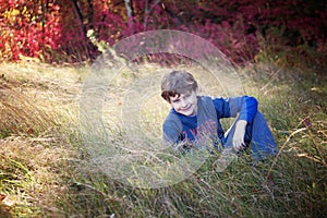 Smiling seven year old boy portrait sitting in field in Autumn