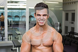 Smiling shirtless muscular man in gym