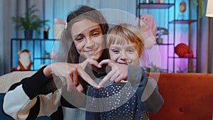 Smiling siblings children girls best friends demonstrates love sign, good feelings, sympathy at home