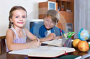 Smiling siblings doing homework with books