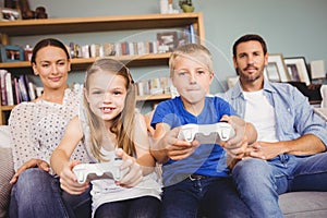 Smiling siblings playing video games with parents