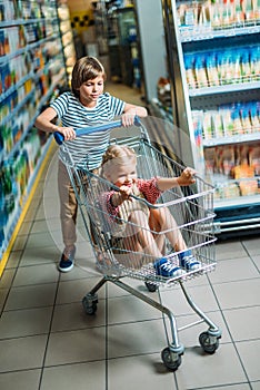 smiling siblings with shopping cart having fun