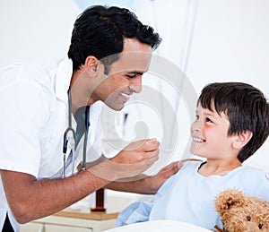 Smiling sick little boy taking medicine