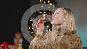 Smiling sincere young woman holding glass of sparkling champagne celebrating New Year or Christmas holidays near