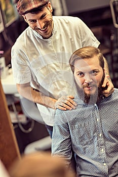 Smiling skillful barber making haircut too bearded customer